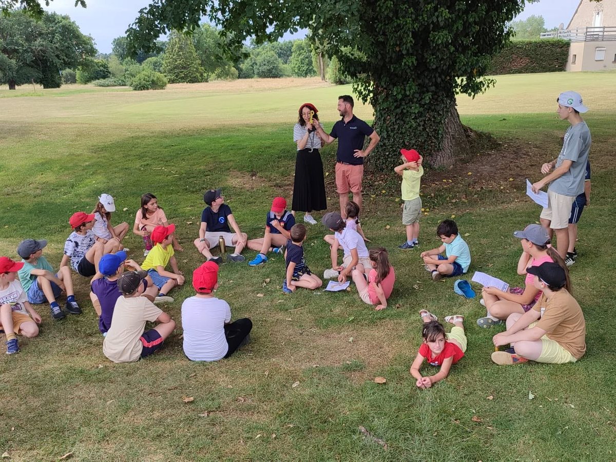 Les enfants de l'école de golf assis en cercle autour des moniteurs