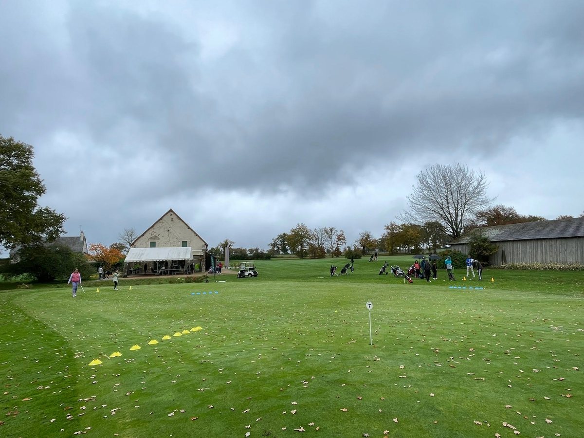 Cours collectif sur l'aire de putting sous un ciel d'automne